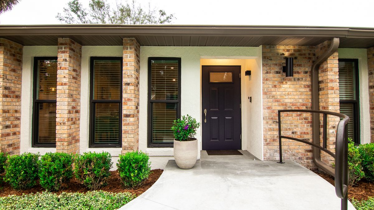 A modern house with a brick exterior and a welcoming front entrance, featuring a potted plant and neatly maintained landscaping.