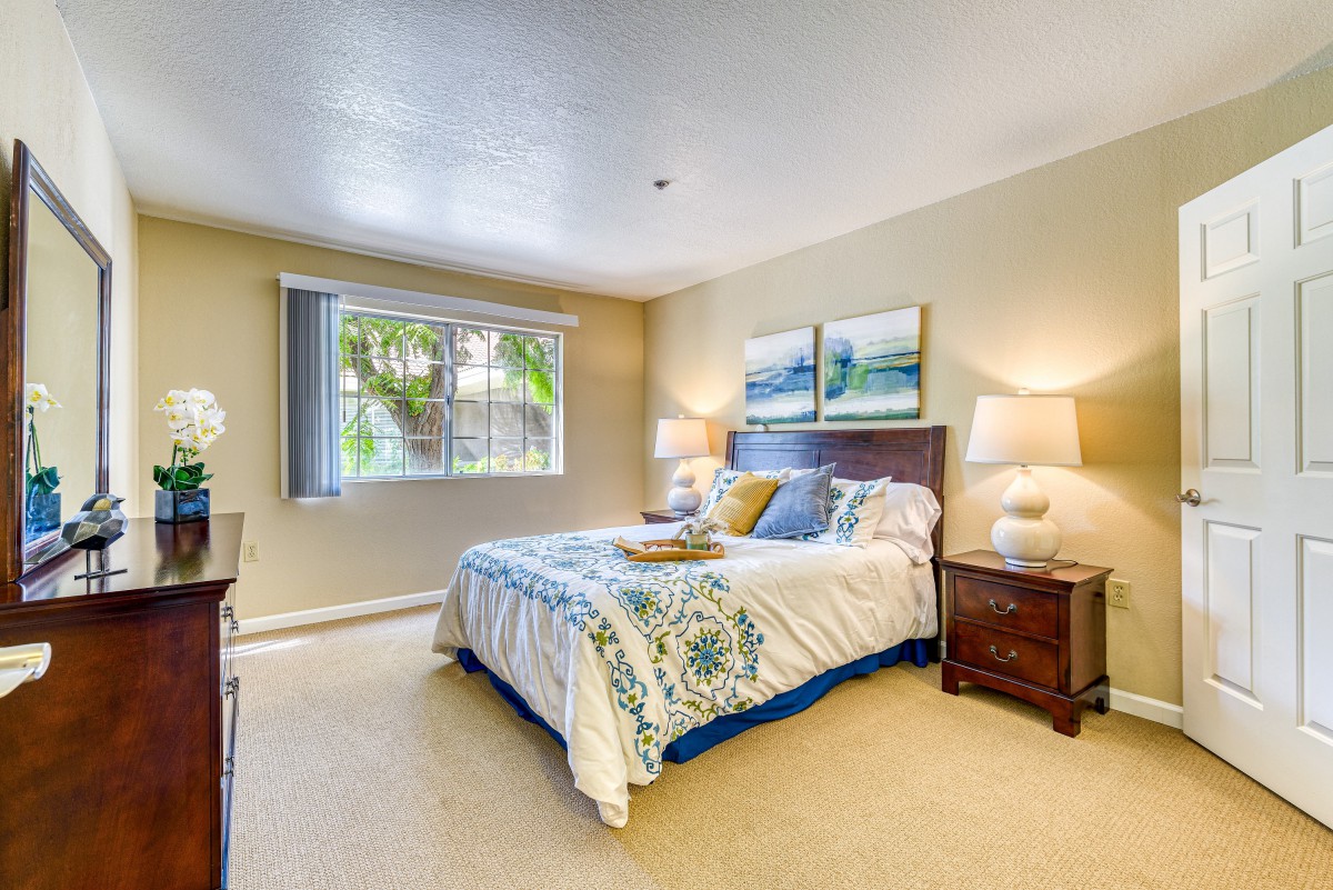 A cozy bedroom with a neatly made bed, bedside tables, and decorative lamps under soft natural light.