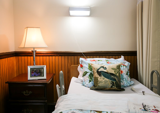 A cozy bedroom corner featuring a neatly made bed with decorative pillows, a bedside lamp, and a framed photo on the nightstand.