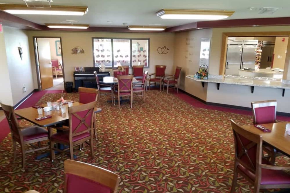 An empty dining room with neatly arranged tables and chairs on a patterned carpet.