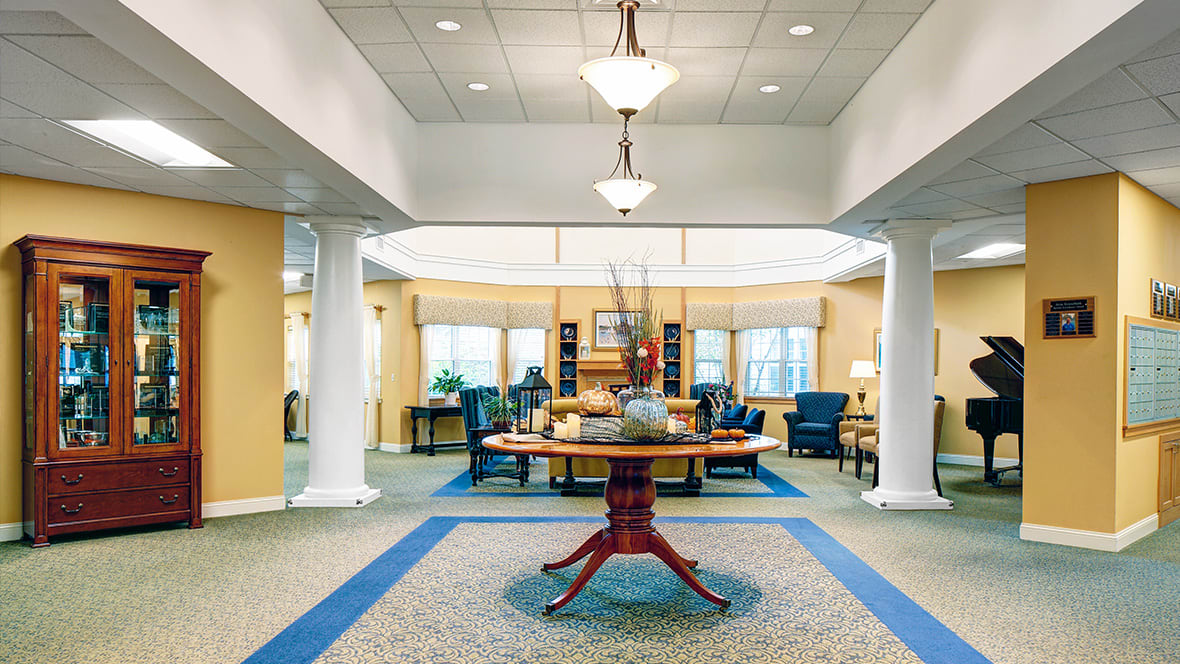 A well-lit lobby featuring a central table, surrounded by chairs and decorative elements.