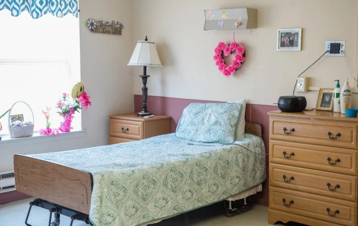 A cozy bedroom with a single bed, lamp, and decorative items.