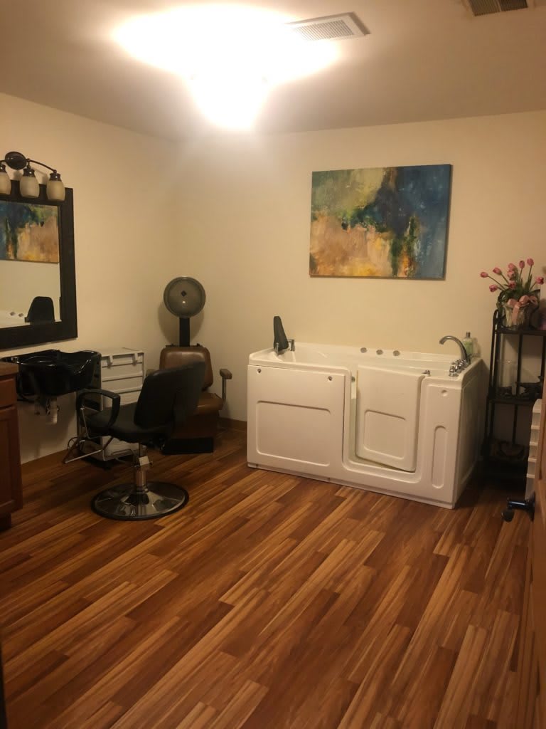 A well-organized salon interior with hairdressing equipment, a chair, mirror, and a bathtub.