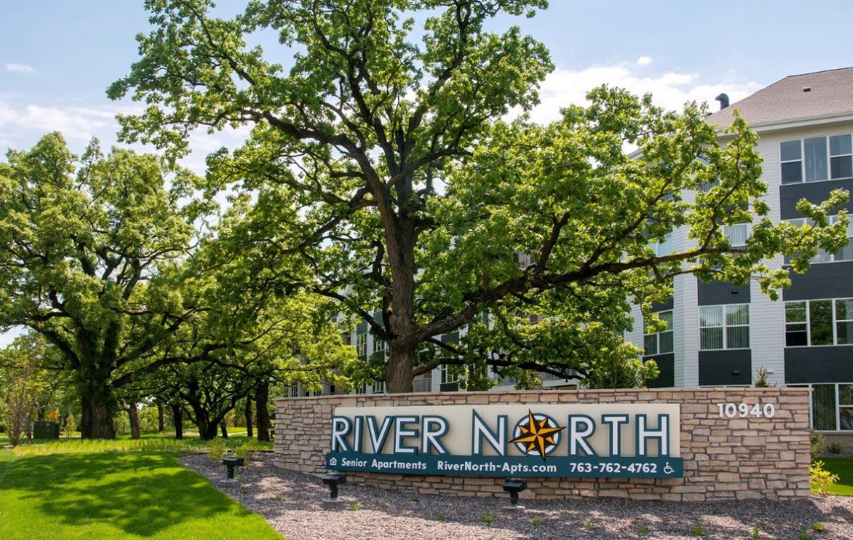 A scenic outdoor view featuring a sign for River North set against a backdrop of lush trees.