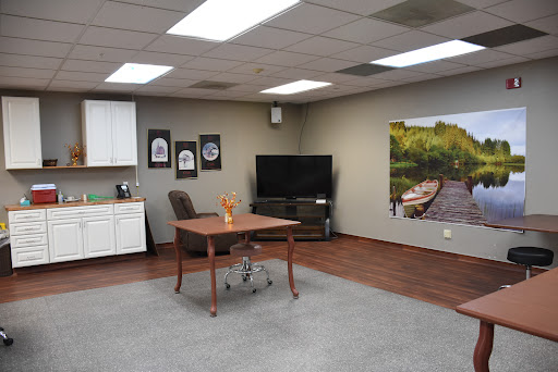 A modern office space featuring a desk, comfortable chair, TV, and decorative art on the walls.