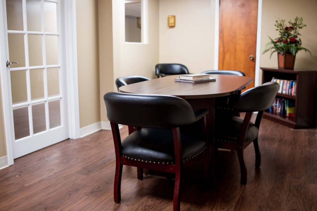 A small conference room with a wooden table and black chairs.
