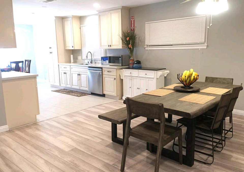 A modern kitchen and dining area with light wood flooring and contemporary furniture.