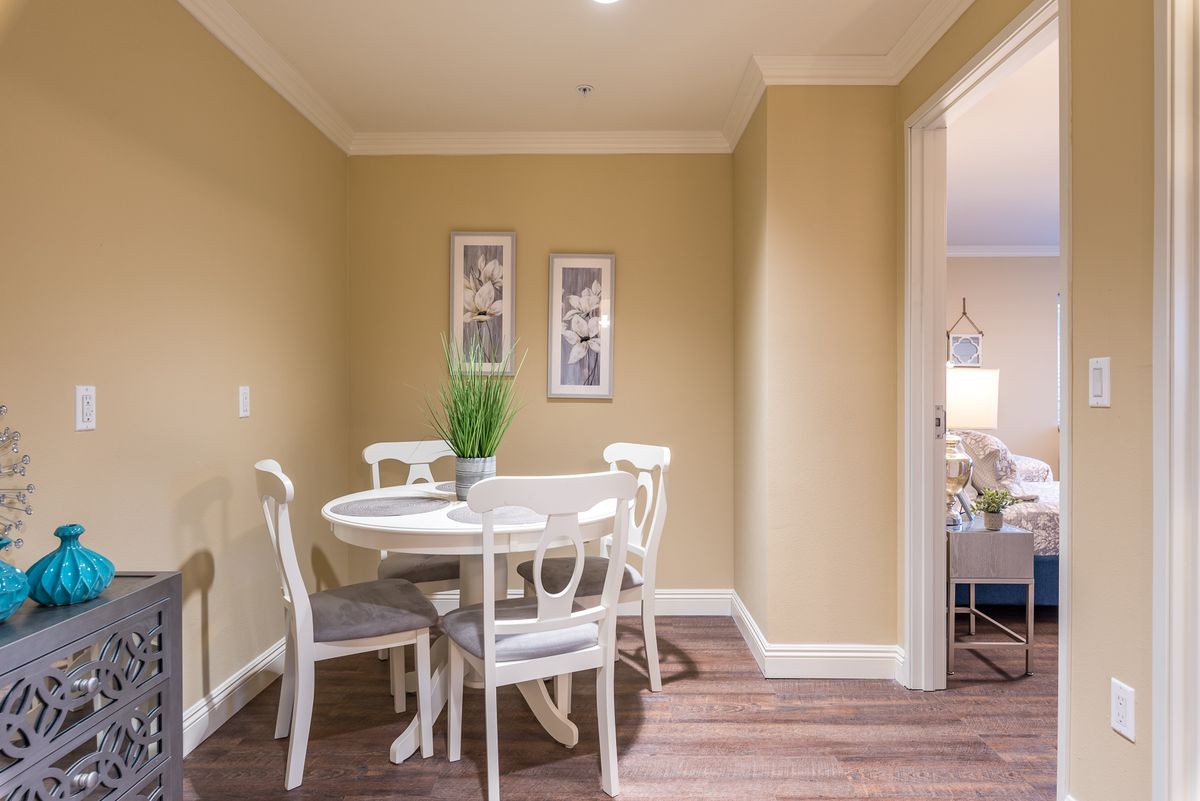 A cozy dining area with a round table and chairs, complemented by wall art and a potted plant.