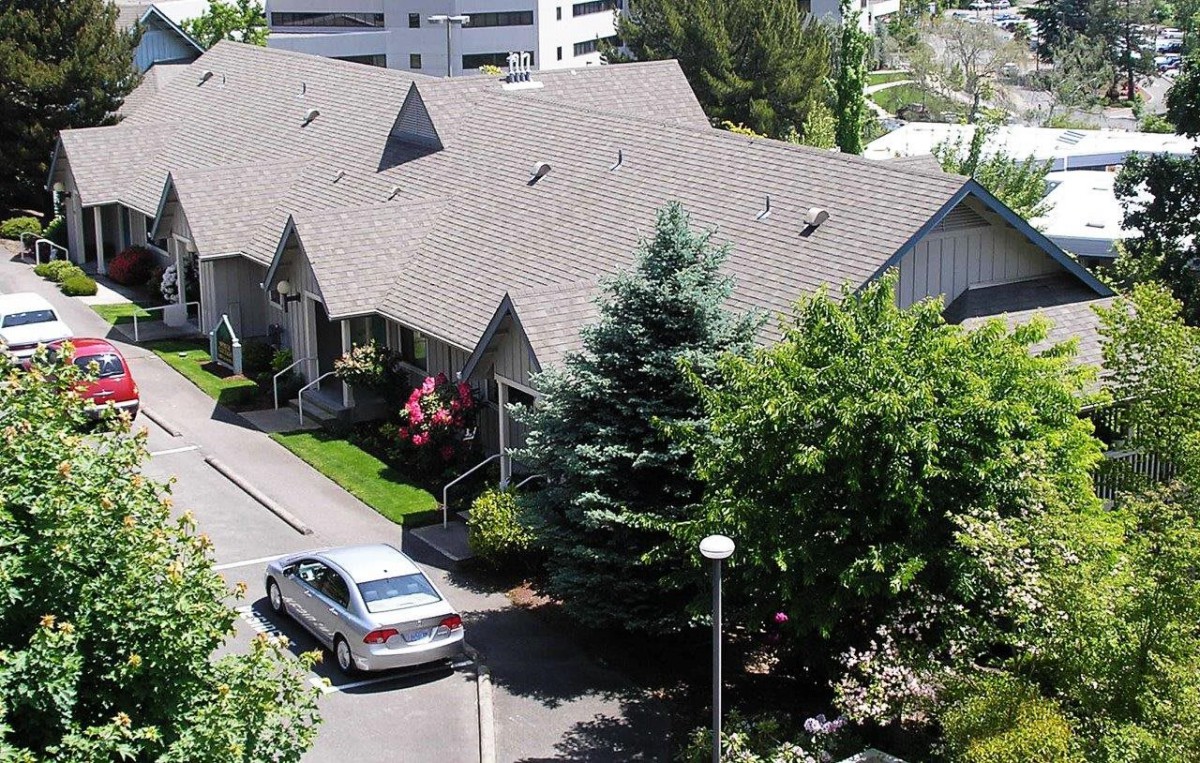 A residential house with a car parked on the driveway, surrounded by trees.