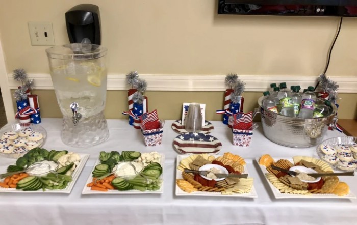 A table set up with a variety of snacks and beverages, featuring patriotic-themed decorations.