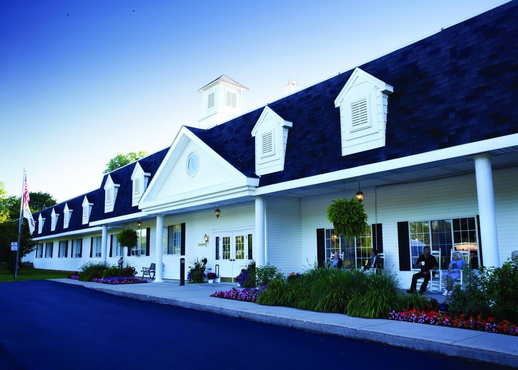 A traditional white building with dormer windows and well-maintained landscaping.