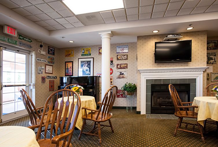 A cozy restaurant interior with wooden chairs and tables, a wall-mounted television, and a fireplace.