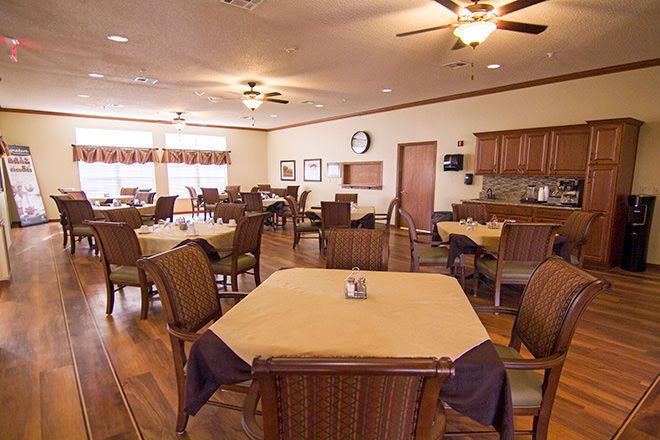 An elegant dining area with neatly arranged tables and chairs, adorned with ceiling fans and wood flooring.