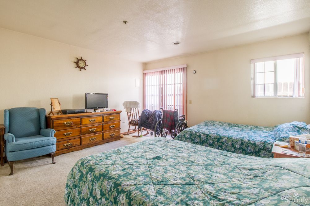 A cozy bedroom with two beds, a television, and nautical decor.