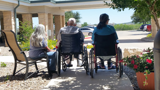 A group of individuals seated in wheelchairs enjoying a sunny day outdoors.