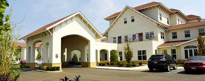 A modern residential building with a covered entrance and landscaped surroundings.