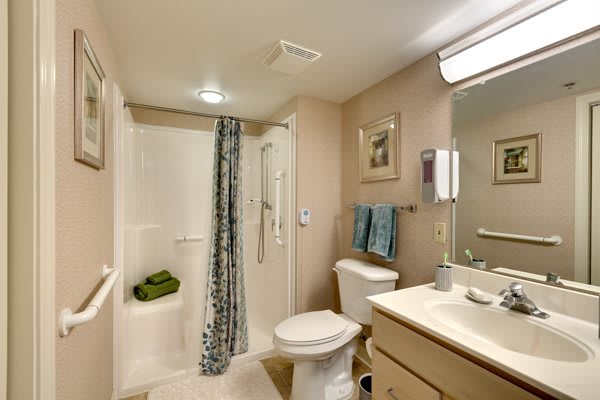 A clean and well-organized bathroom with a shower, toilet, sink, and mirror.