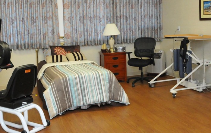 A cozy bedroom with a single bed, striped bedding, and an office chair.