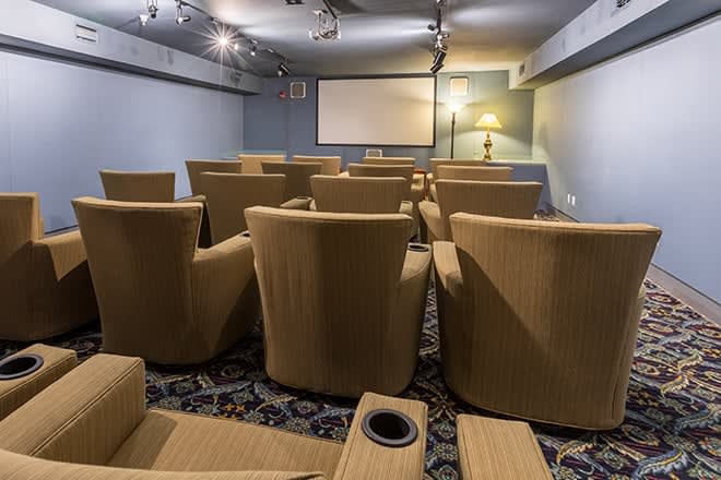 A cozy home theater with comfortable seating facing a projector screen.
