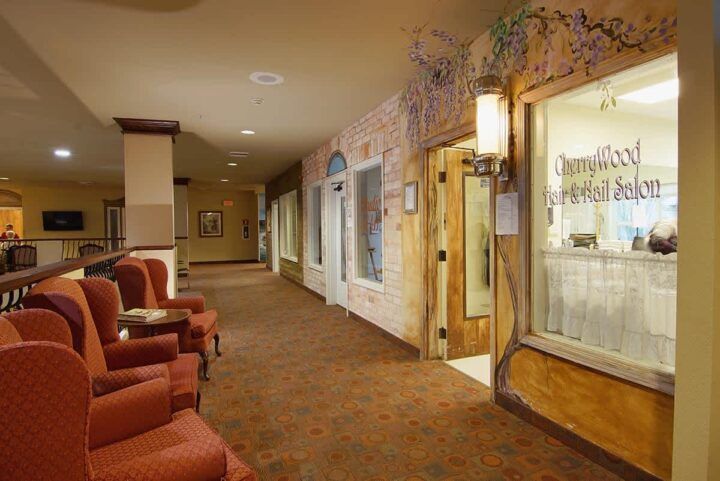 A warmly lit hotel hallway featuring comfortable seating and decorative wall art.