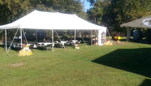 A spacious outdoor tent set up with tables on a grassy area, perfect for an event or gathering.