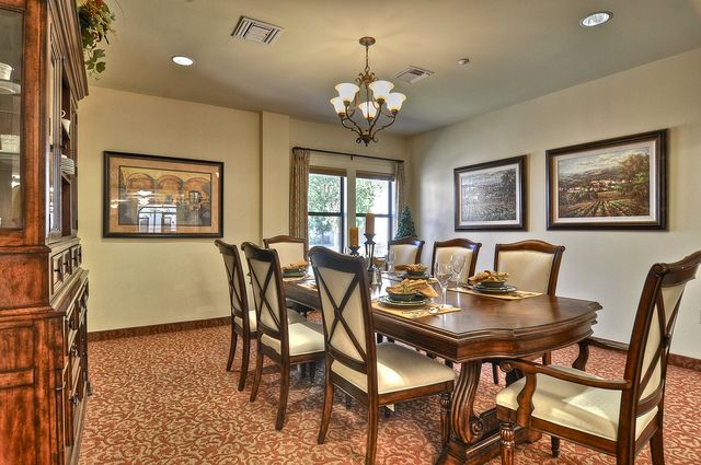 A well-decorated dining room featuring a large table with chairs and elegant lighting.