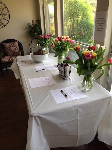 A beautifully decorated event table with tulip arrangements and sign-in sheets.