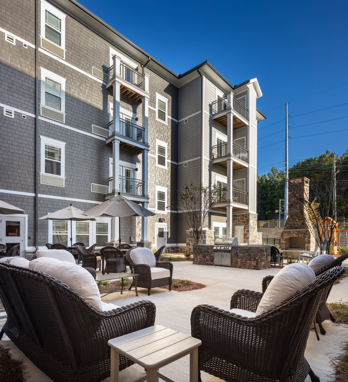 A modern apartment building with a spacious outdoor patio area featuring comfortable seating.