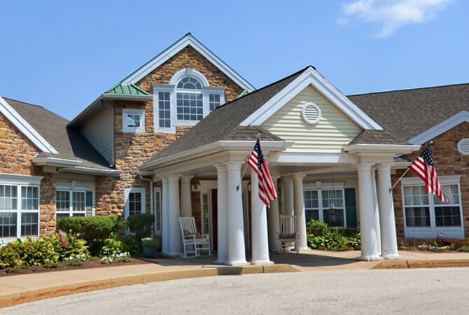 A residential house with a prominent entrance featuring columns and an American flag.