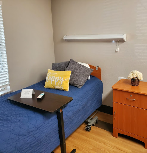 A cozy and organized small bedroom featuring a blue bed and wooden furniture.