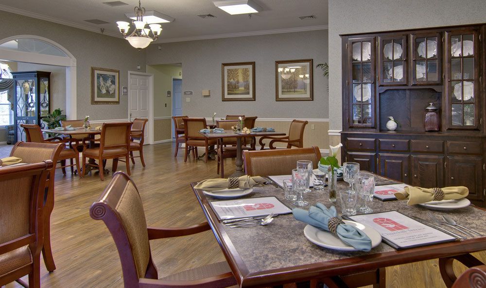 A neatly arranged dining room with elegantly set tables and a chandelier overhead.
