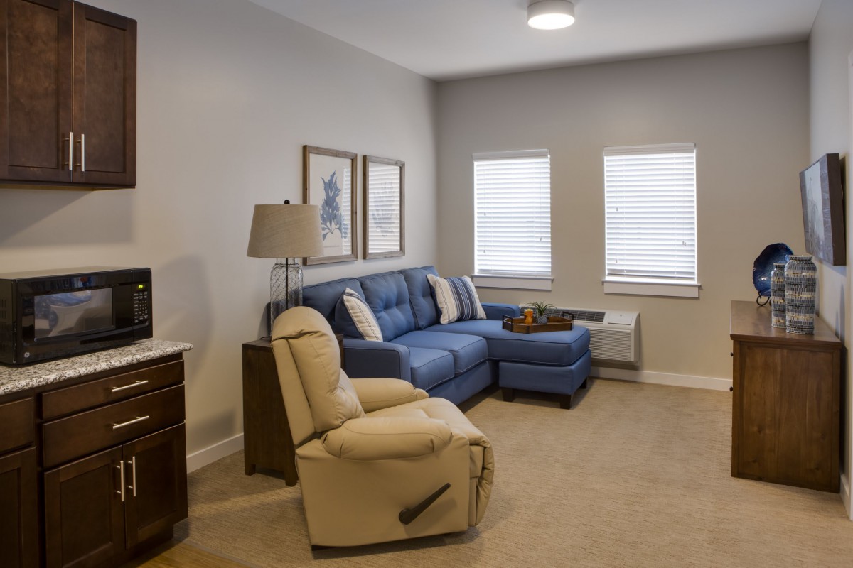 A cozy living room with a blue sofa, beige armchair, and decorative elements.