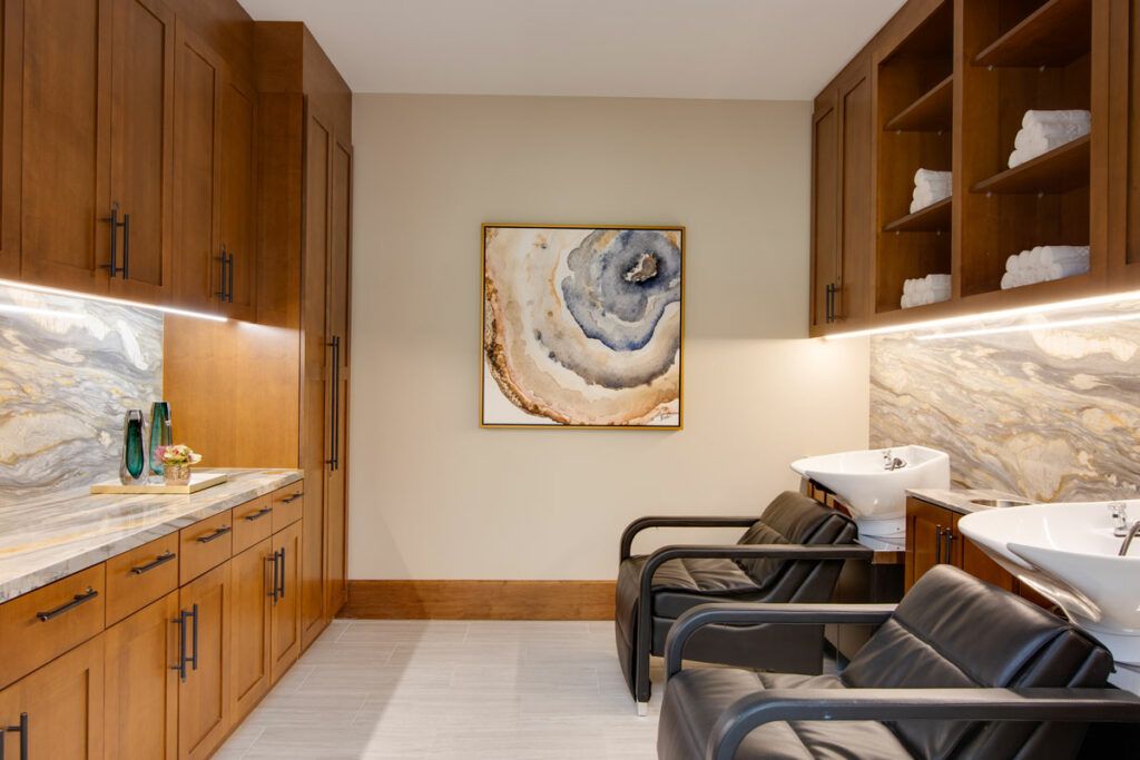 A modern spa interior with wooden cabinets and comfortable seating, featuring abstract artwork on the wall.