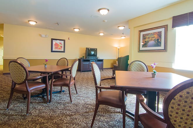A cozy dining area with tables and chairs, a television, and framed artwork on the walls.