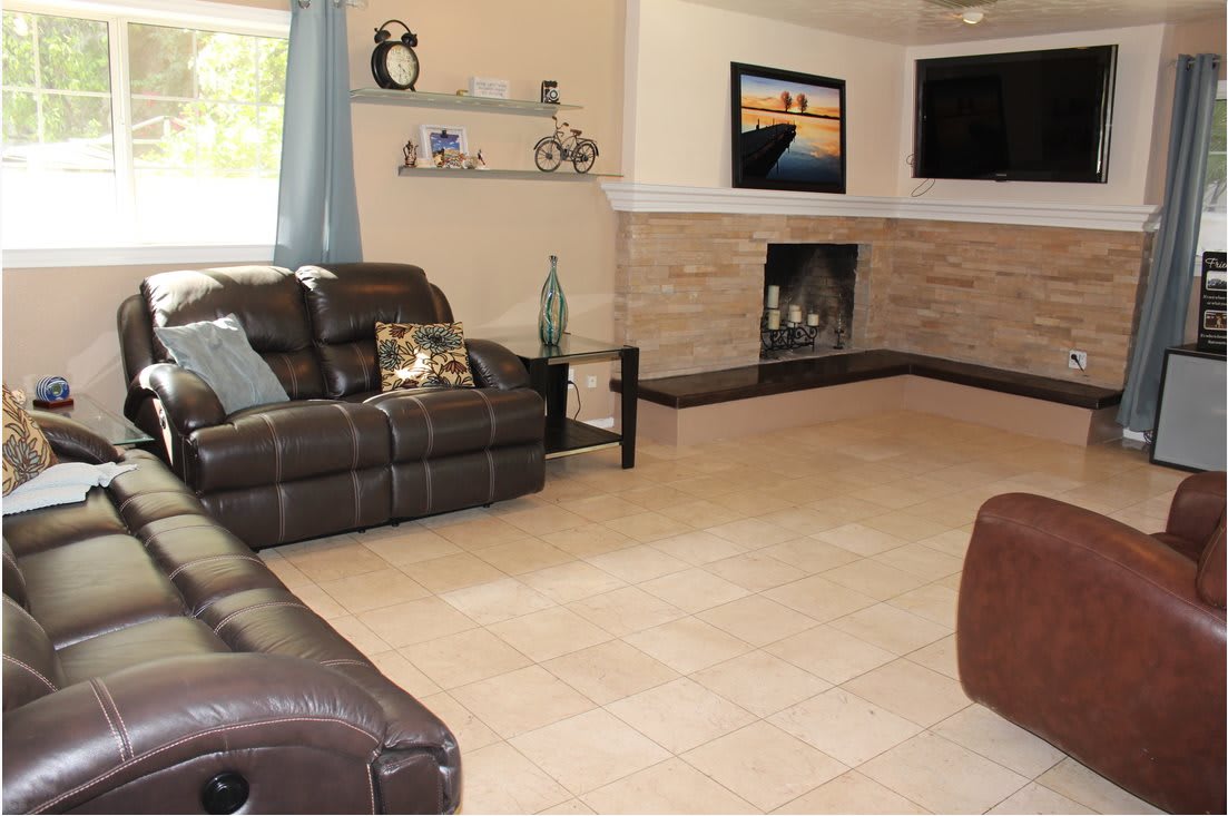 A cozy living room with leather sofas, a fireplace, and a mounted television.