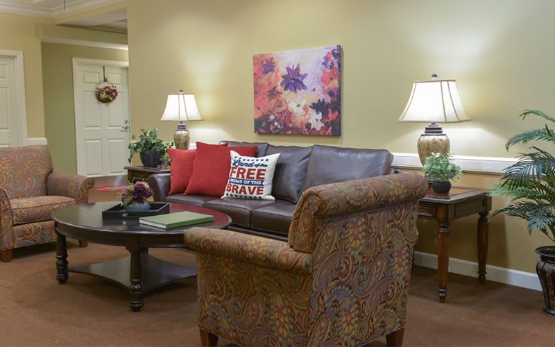 A cozy living room with a leather sofa, patterned armchair, and decorative pillows, complemented by warm lighting and wall art.