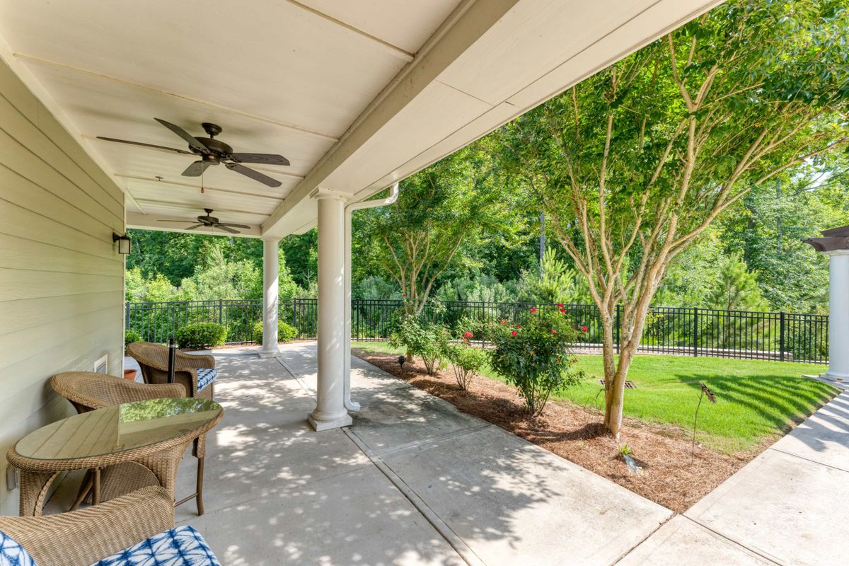 A bright and relaxing patio with ceiling fans, surrounded by lush greenery.