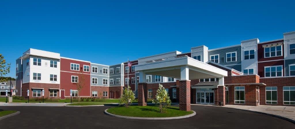 A modern residential building with a landscaped entrance and clear blue skies.