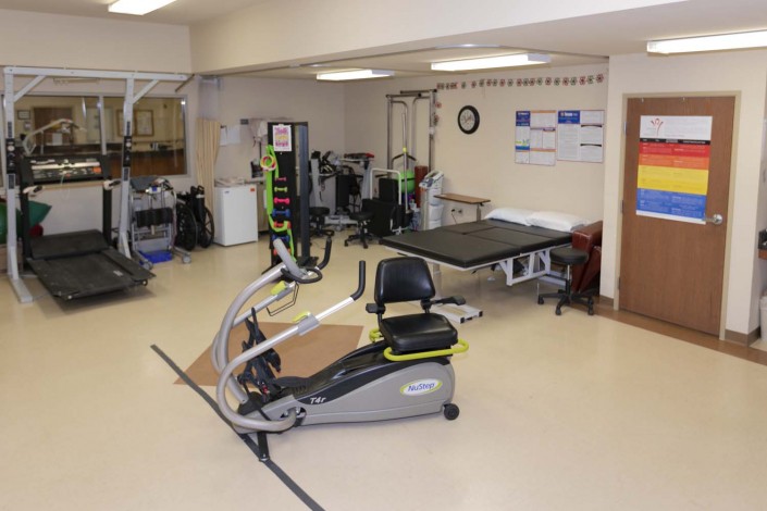A therapy room equipped with an exercise bike and various rehabilitation equipment.