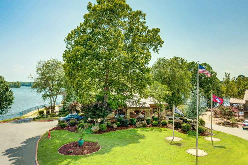 A scenic view of a house surrounded by lush greenery and a well-maintained lawn, with a lake visible in the background.
