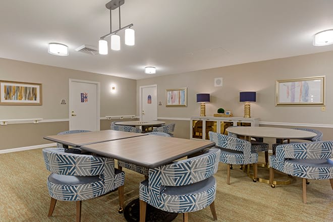 A well-lit conference room with tables and patterned chairs arranged for a meeting.