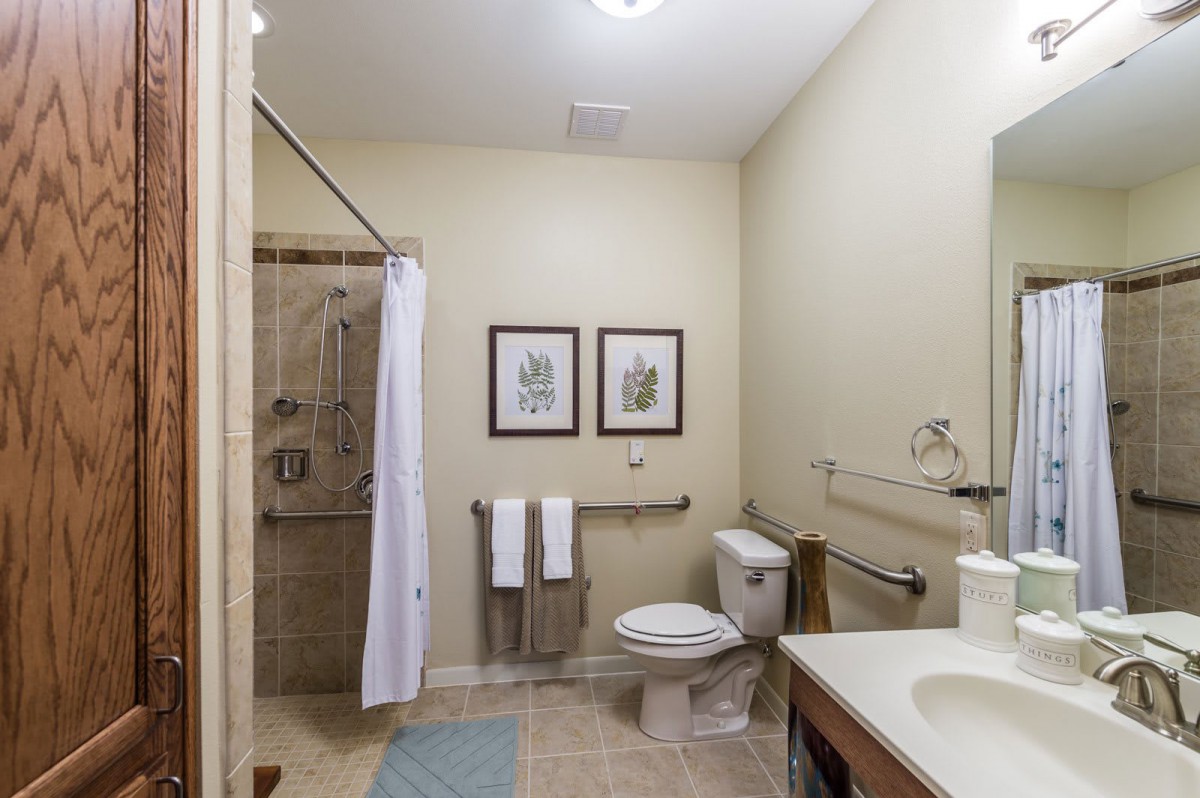 A clean and modern bathroom featuring a shower, toilet, and sink with light decor.