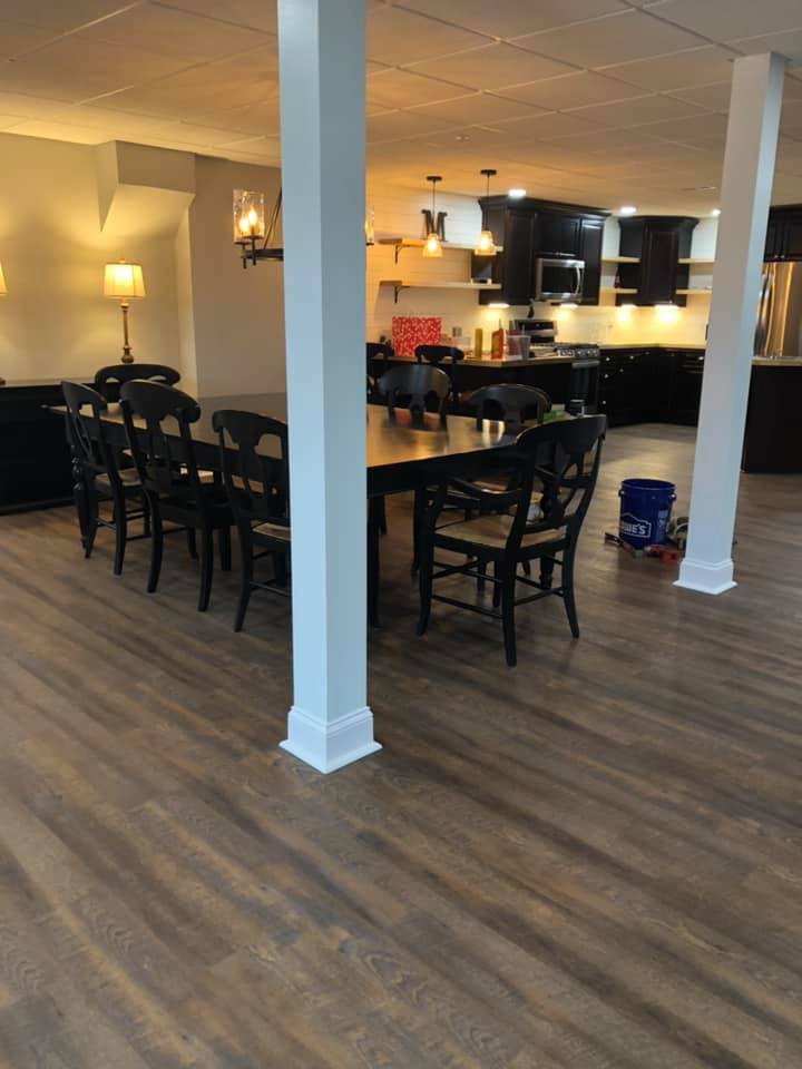 A spacious dining area with a long table and chairs, leading into a modern kitchen.