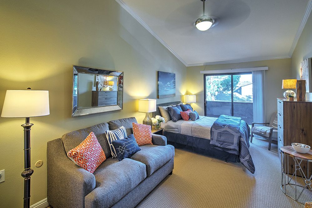 A cozy bedroom with a comfortable sofa and a neatly made bed, complemented by stylish decor and warm lighting.