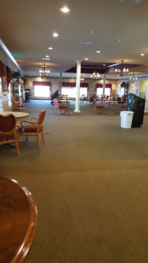 A spacious dining area featuring empty tables and chairs, illuminated by soft lighting.