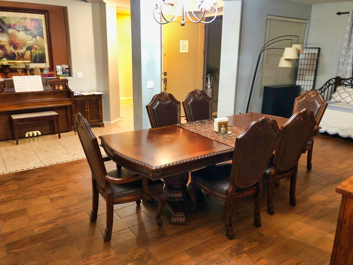 A cozy dining room with a wooden table and chairs, illuminated by a chandelier.