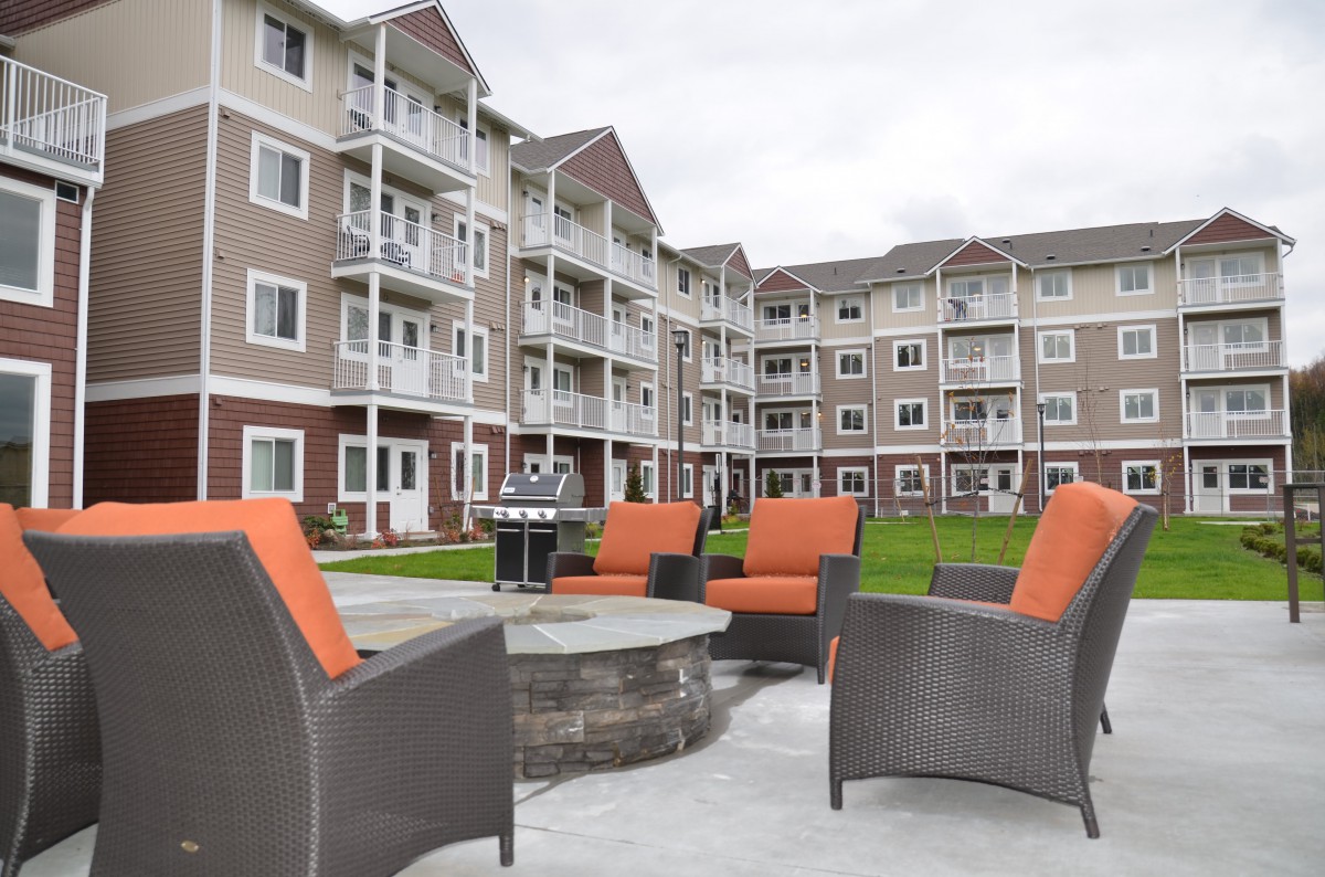 An outdoor seating area with a fire pit in front of an apartment building.