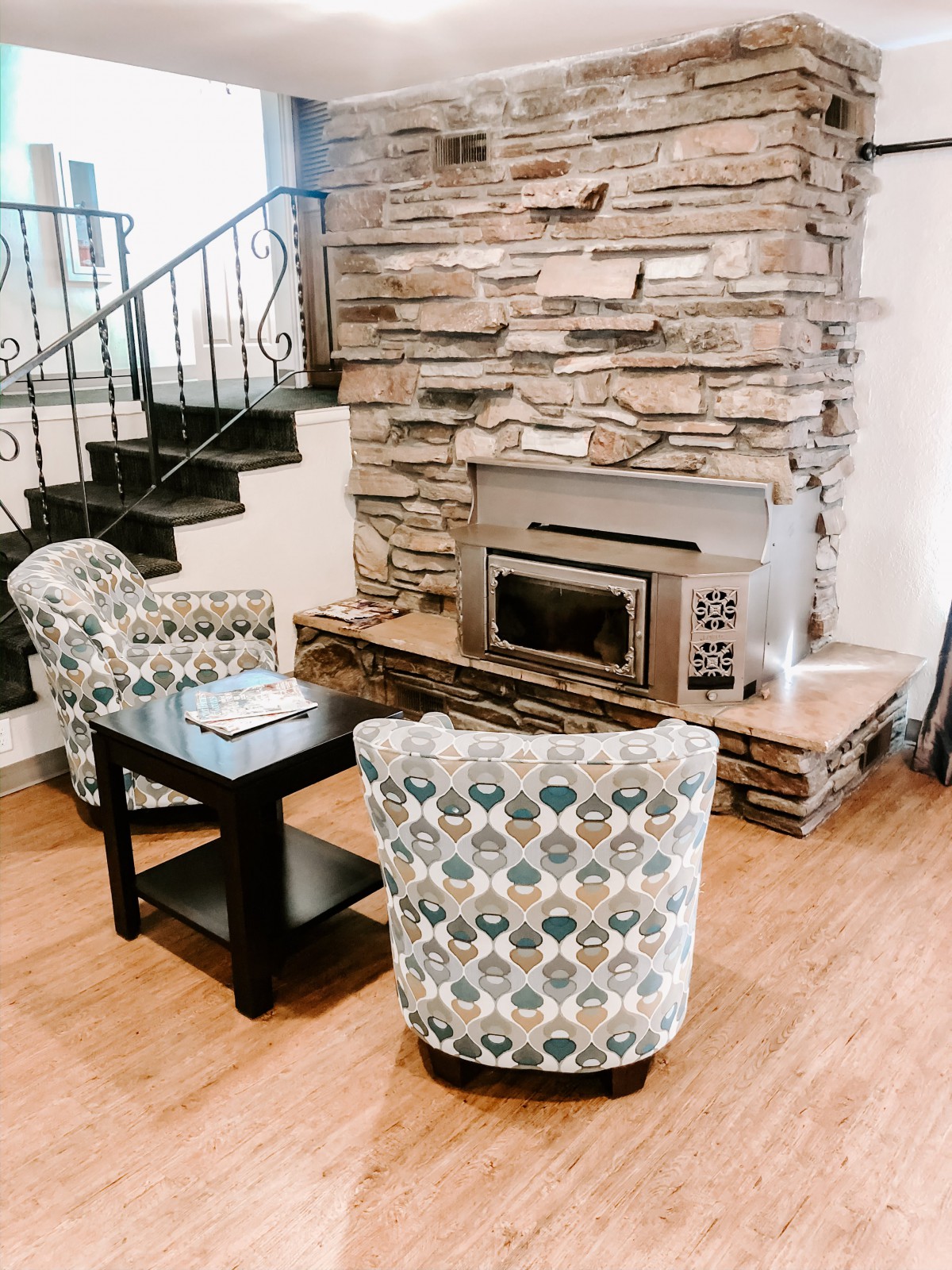 A cozy living room with patterned armchairs and a stone fireplace.