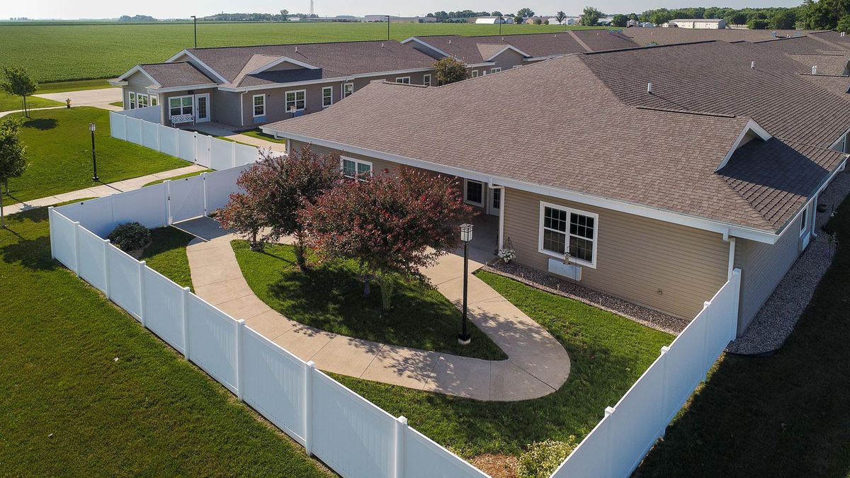 Aerial view of a suburban house with a fenced yard and landscaped pathway.