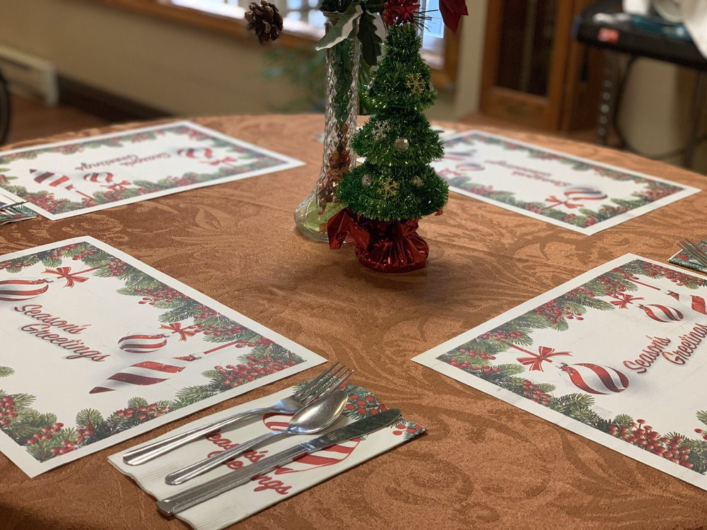 A festive Christmas-themed table setting with holiday place mats and a decorative centerpiece.